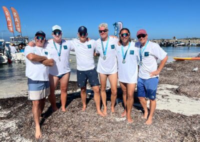 Group of six Floreat Freestylers participants on the beach after the Port to Pub swim, wearing finisher medals