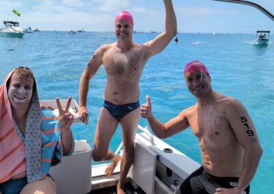Three Floreat Freestylers participants celebrating on a boat after the Port to Pub swim